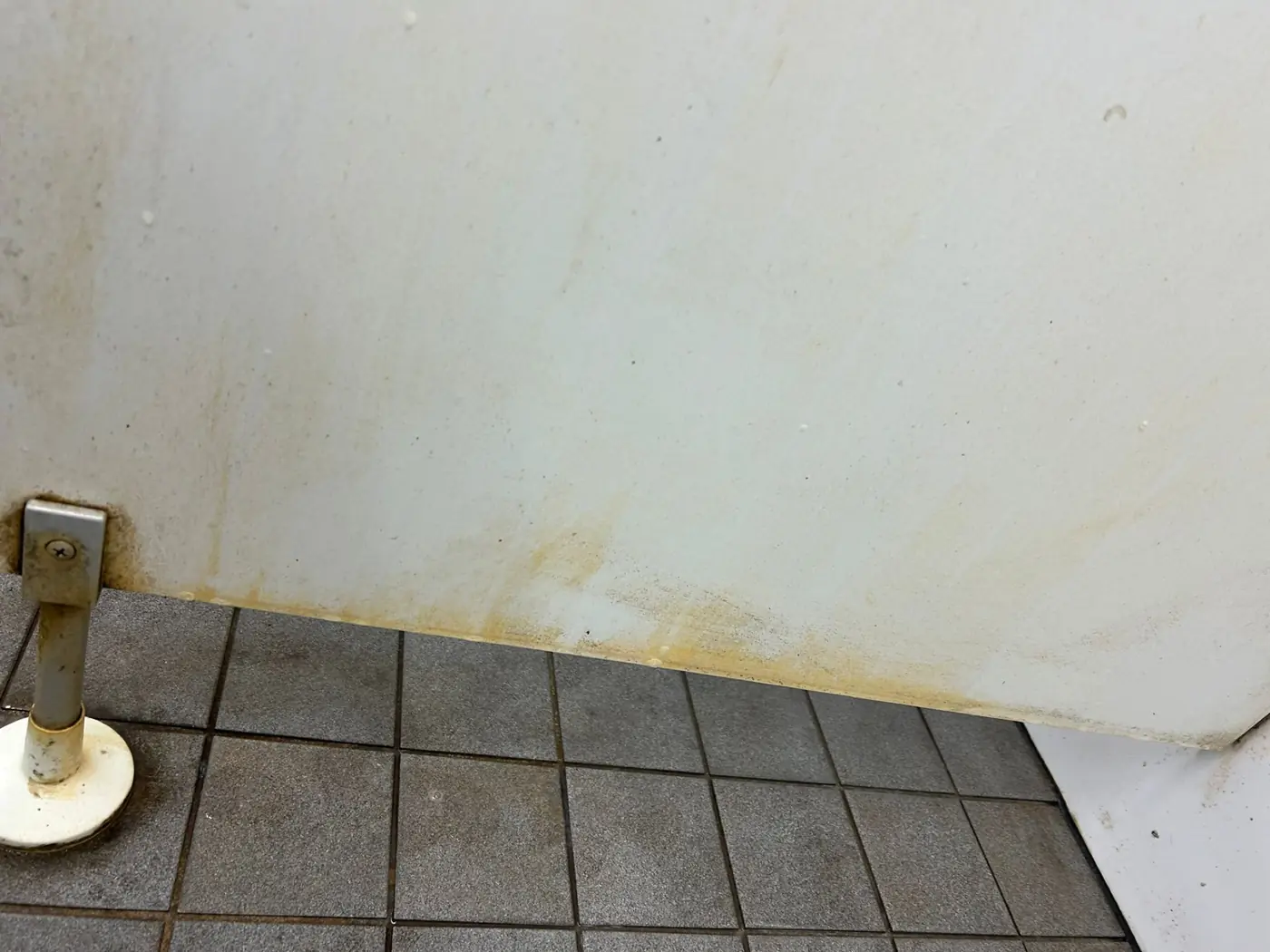 Sanitärbereich mit Kalk, Rost und verfärbten Bodenfugen vor der Grundreinigung