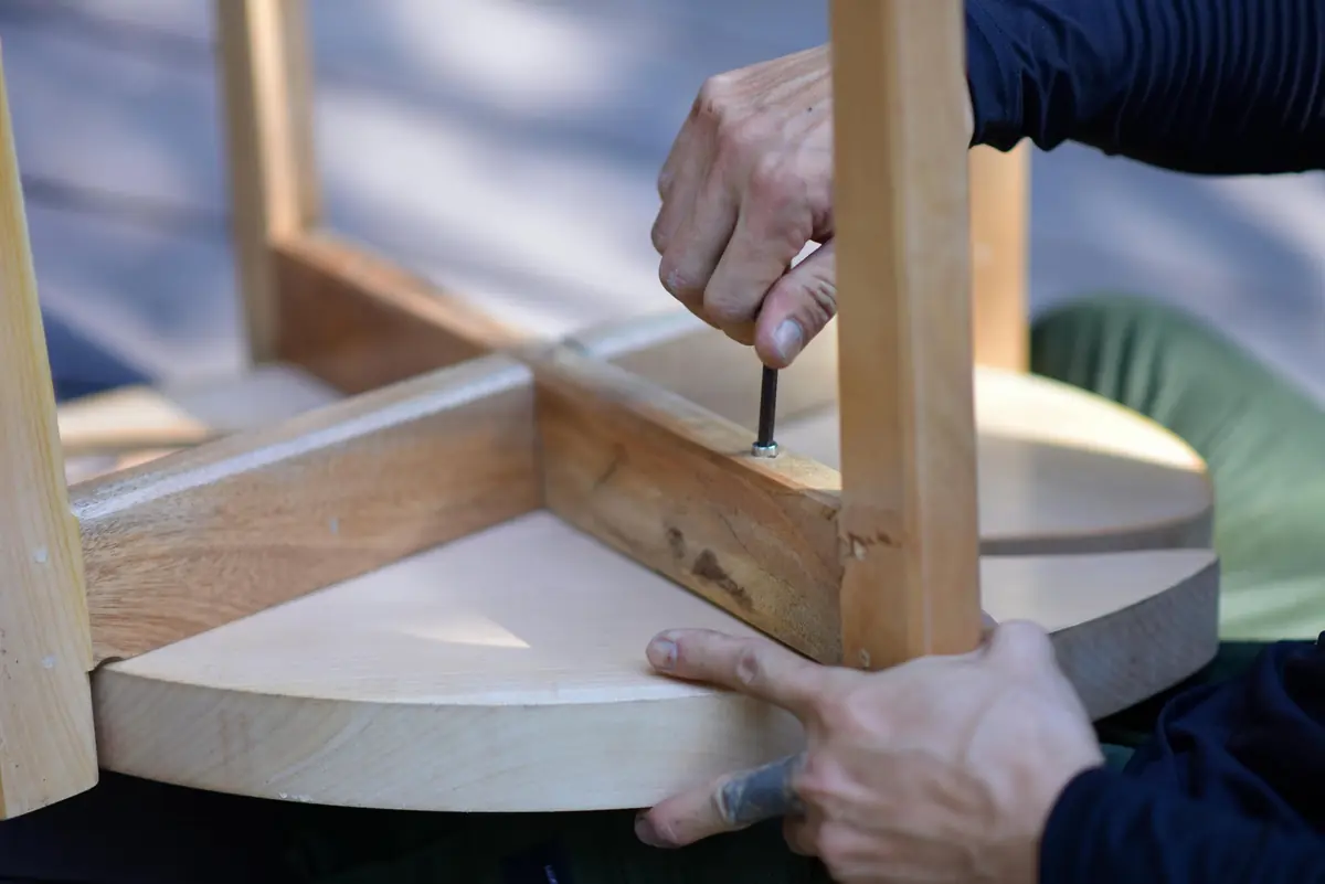 Möbelaufbau in einer Wohnung: zwei Hände verschrauben eine Holzplatte